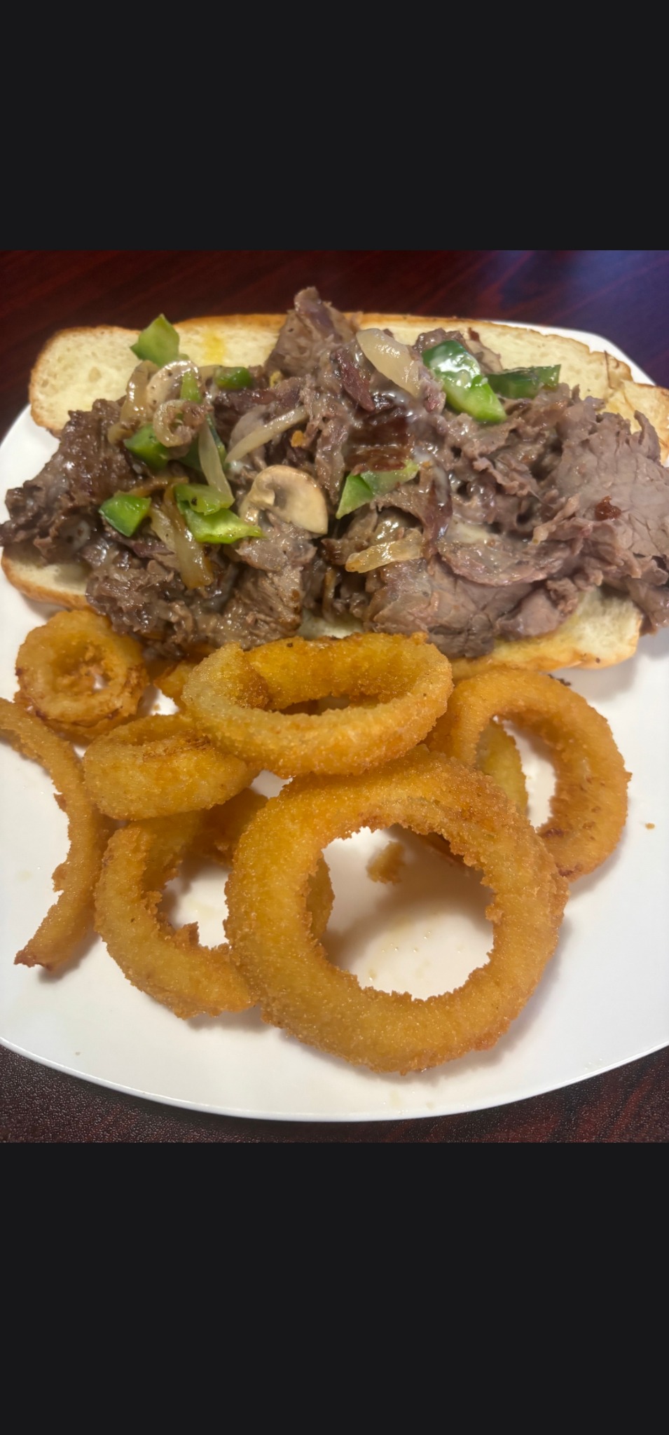 Cheesesteak with peppers, onions, mushrooms, and onion rings